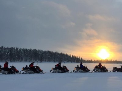 Procession de motoneige au coucher du soleil